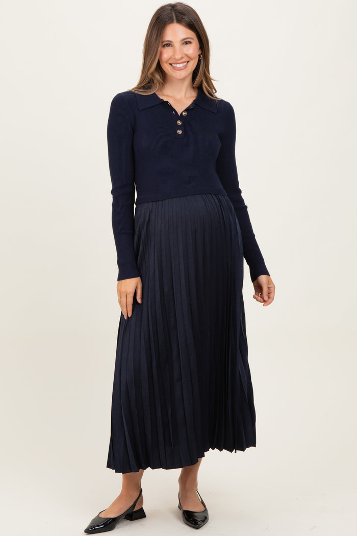 woman wearing a navy blue maternity dress with a collared neck and pleated skirt, showcasing her baby bump.