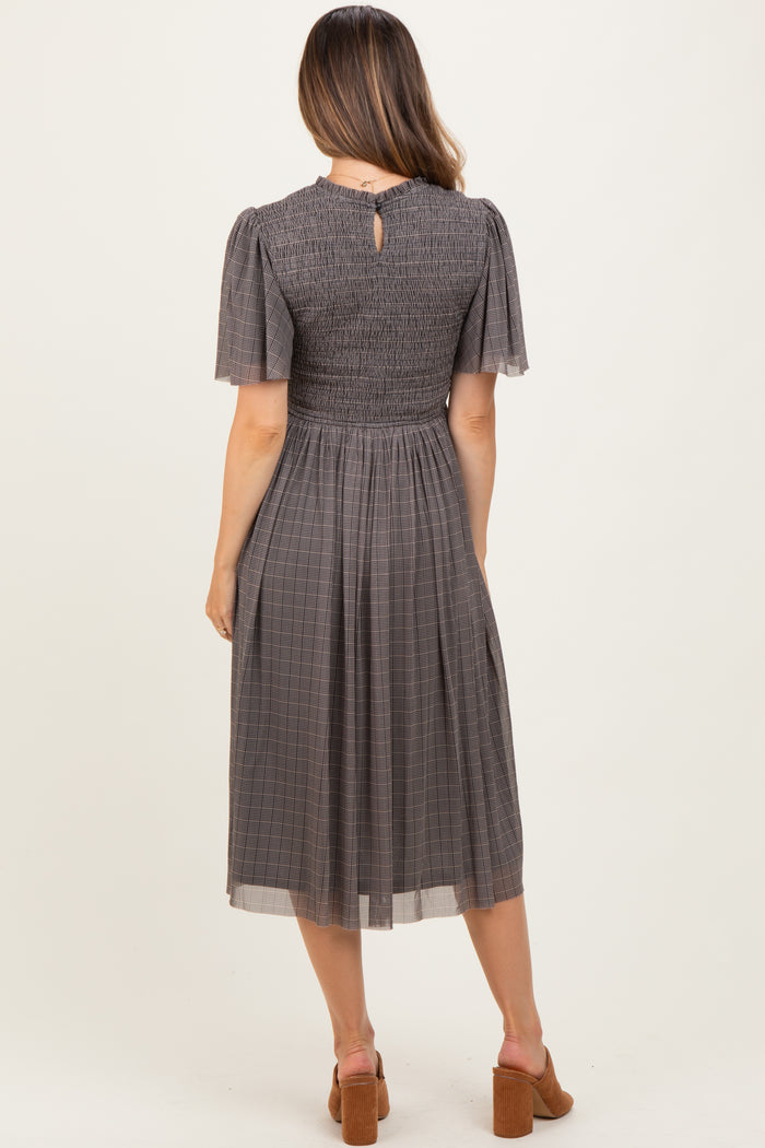 woman wearing a gray smocked maternity dress with short puff sleeves and a keyhole back detail