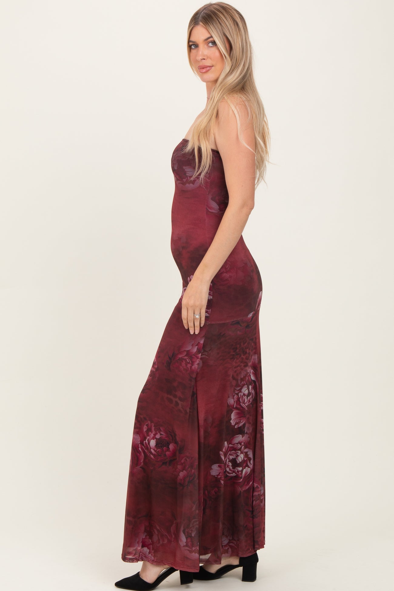 woman wearing a burgundy floral maxi dress with a fitted silhouette and side slit, posing sideways with long hair down