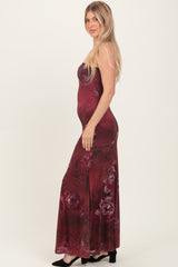 woman wearing a burgundy floral maxi dress with a fitted silhouette and side slit, posing sideways with long hair down