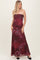 woman wearing a burgundy strapless maxi dress with floral prints and a flowing silhouette