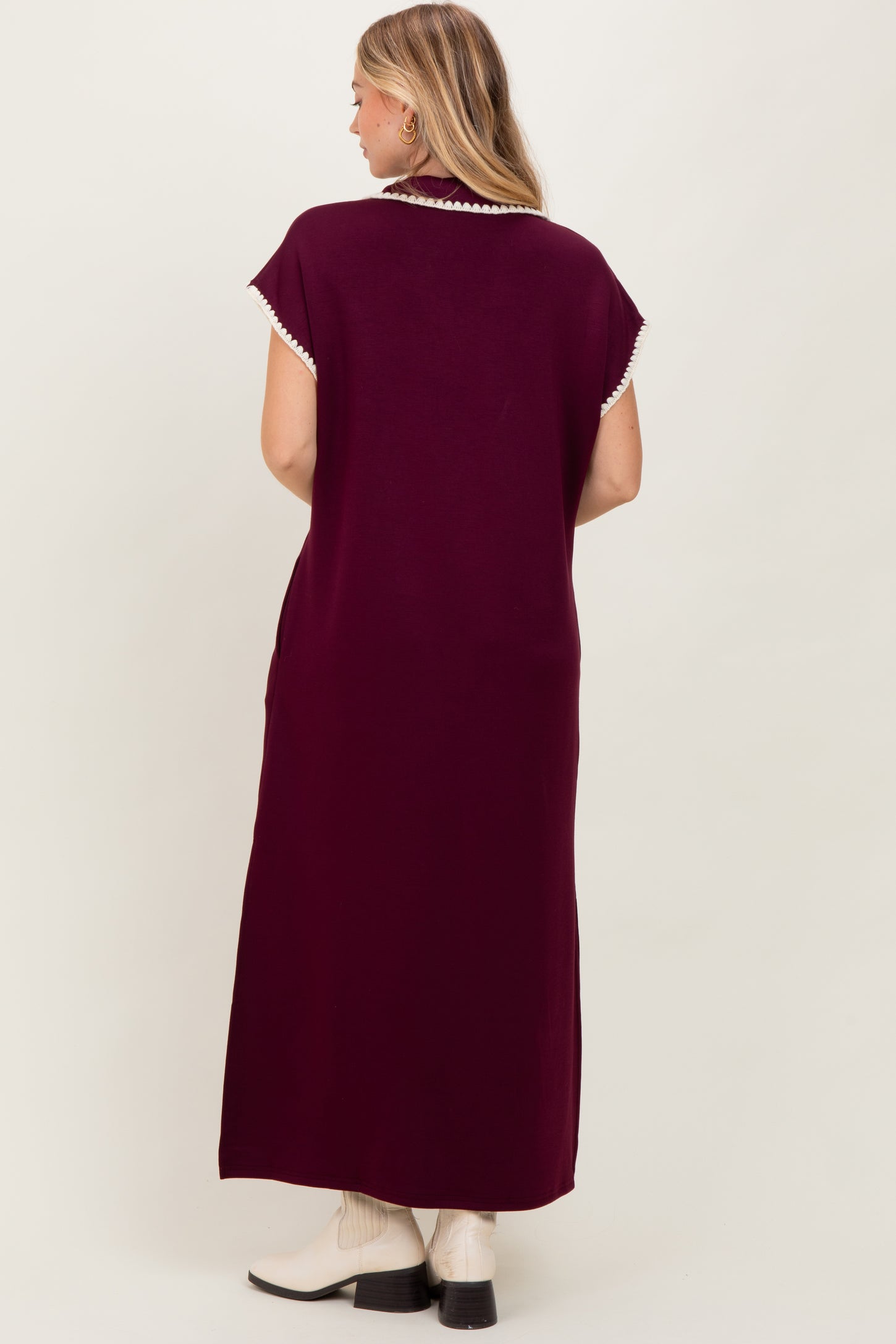 woman wearing a burgundy maxi dress with decorative trim on the neckline and short sleeves, shown from the back