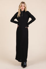 woman wearing a black long sleeve maxi dress with a zippered neckline and a fitted silhouette