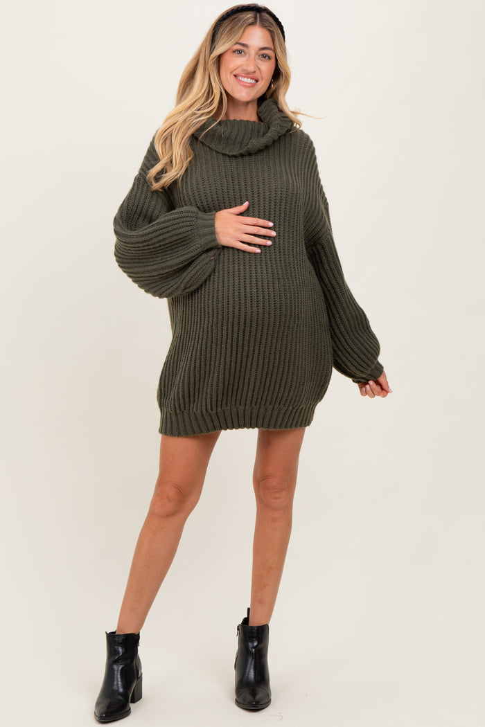 woman wearing a green ribbed maternity sweater dress with a cowl neck and a visible baby bump