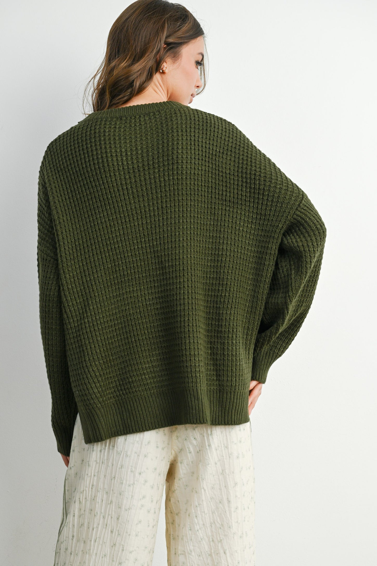 woman wearing an olive green oversized knit sweater with a relaxed fit and dropped shoulders, viewed from the back