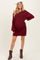 woman wearing a burgundy knitted off-shoulder maternity dress with long sleeves and a relaxed fit