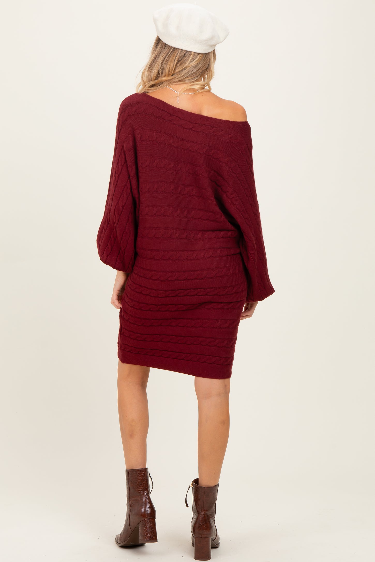 woman wearing a burgundy off-the-shoulder cable knit maternity sweater dress, view from the back