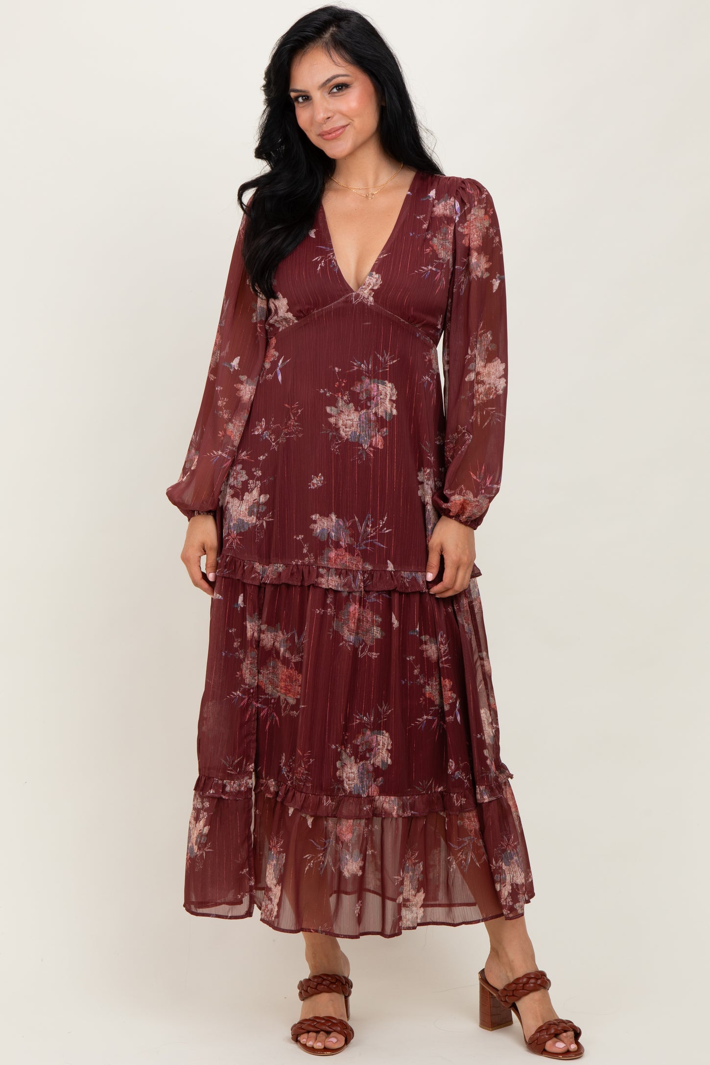 woman wearing a burgundy floral maxi dress with long sleeves and a tiered skirt