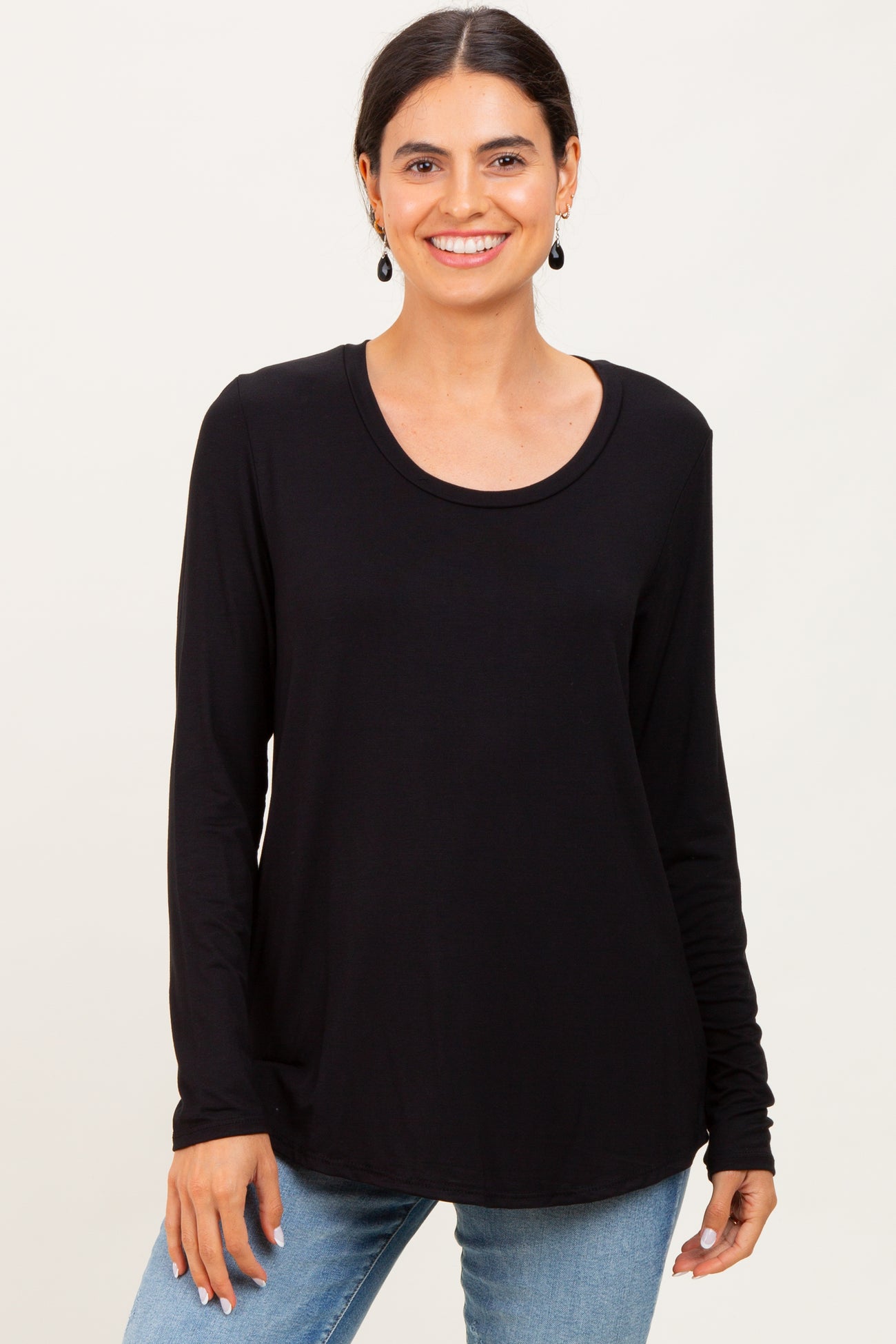 woman wearing a black long sleeve top with a rounded neckline and smiling