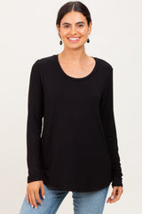 woman wearing a black long sleeve top with a rounded neckline and smiling