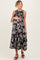 woman wearing a floral black maternity dress with a tiered skirt and holding her baby bump