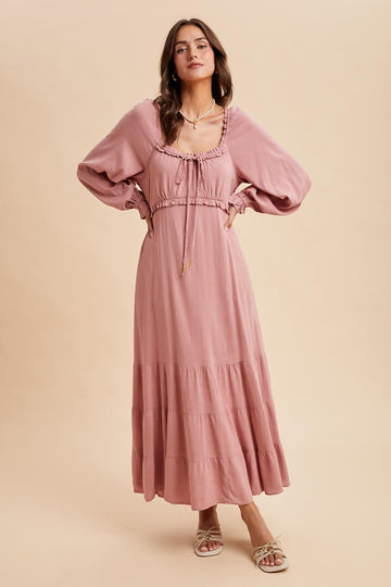 woman wearing a dusty pink long sleeve maxi dress with a tiered skirt and drawstring detail around the neckline