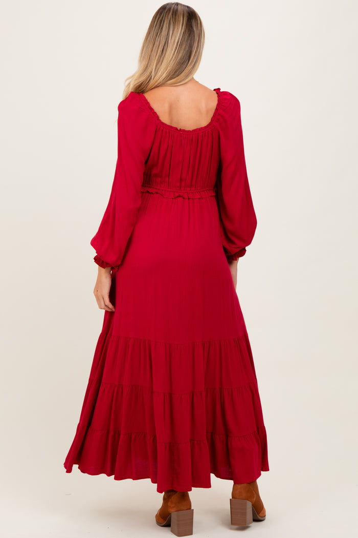 woman wearing a long red maternity dress with tiered ruffles and long sleeves, showing her back
