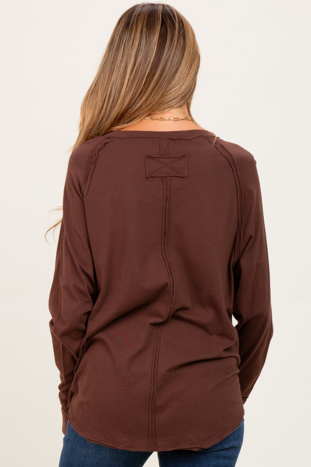 woman wearing a brown long sleeve maternity top with a relaxed fit and back seam detail
