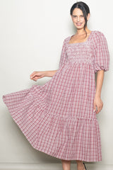 woman wearing a red and white checked puff sleeve midi dress with a smocked bodice and tiered hem