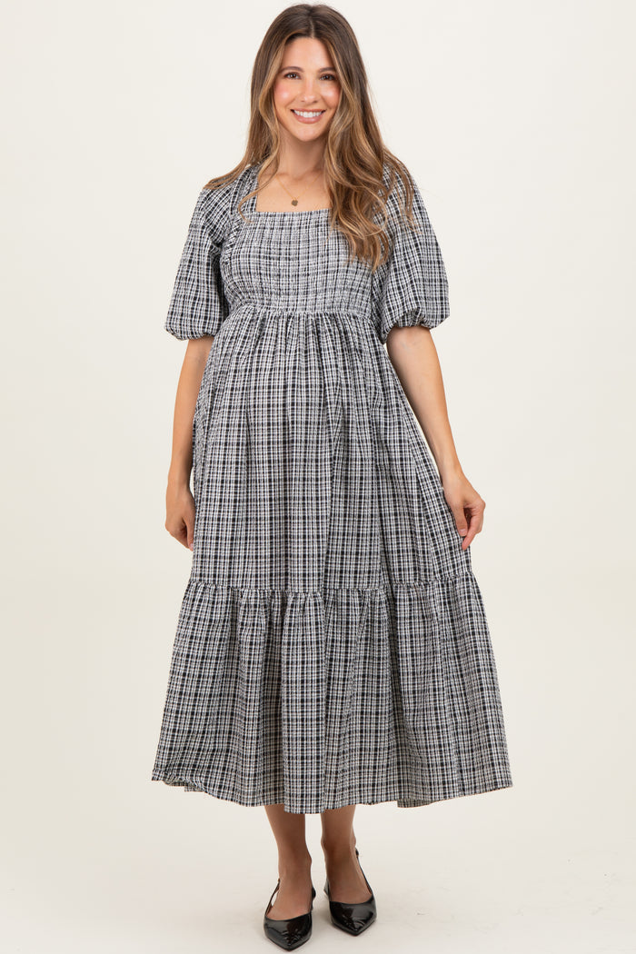 woman wearing a black and white checkered maternity dress with puff sleeves and tiered skirt, showcasing her baby bump