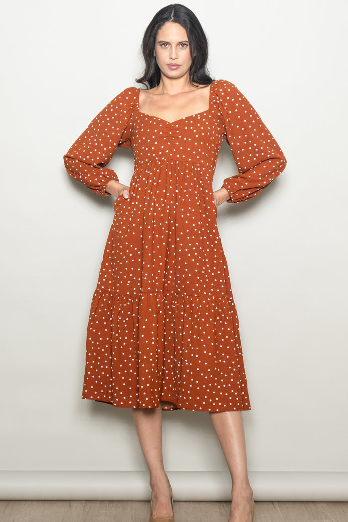 woman wearing a rust long sleeve polka dot midi dress with a square neckline and tiered skirt