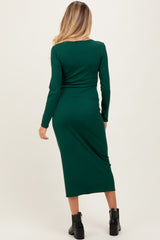 woman wearing a fitted dark green long sleeve maternity dress in a mid-length style, viewed from the back