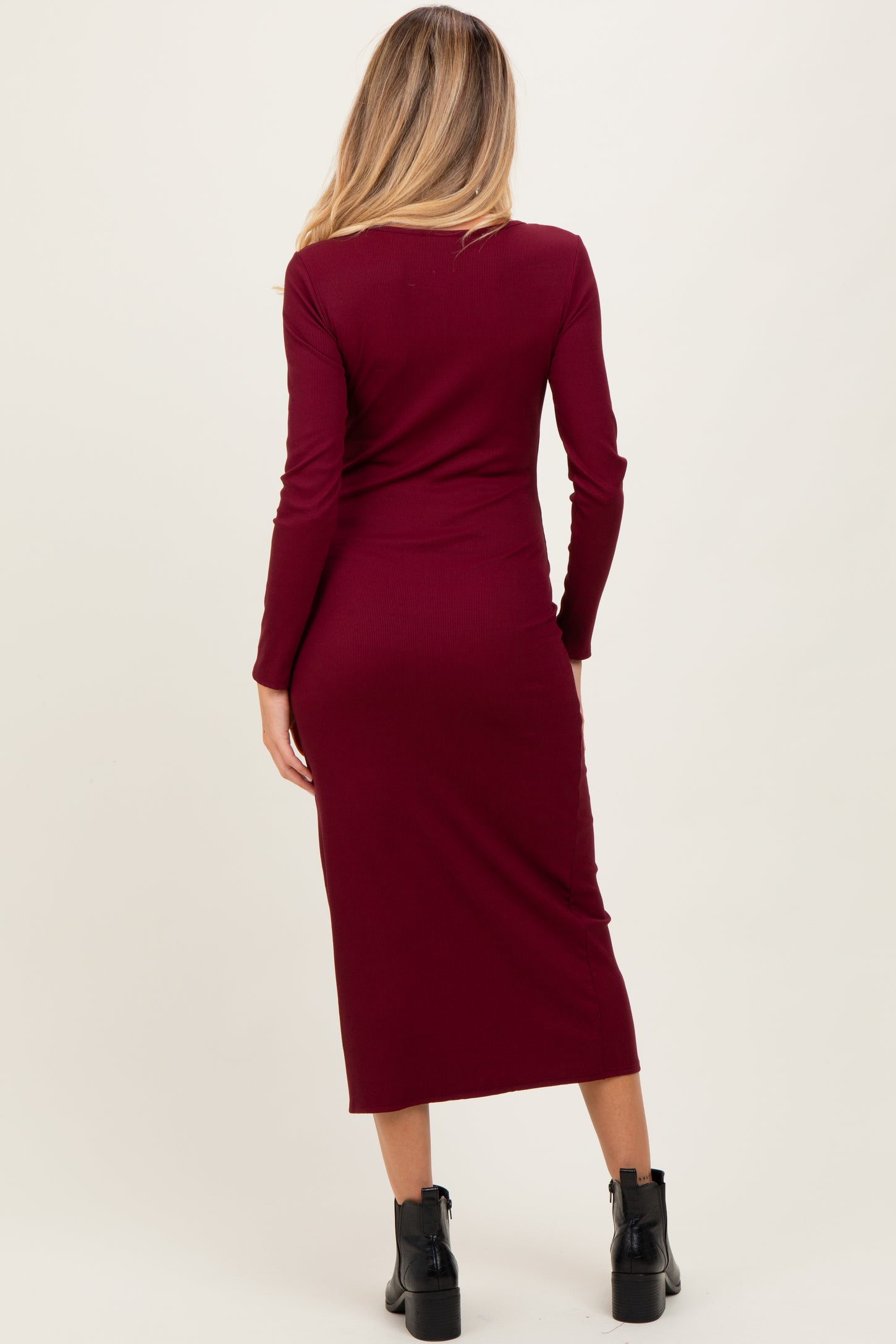 woman wearing a burgundy long sleeve maternity dress, shown from the back, with a fitted silhouette and midi length