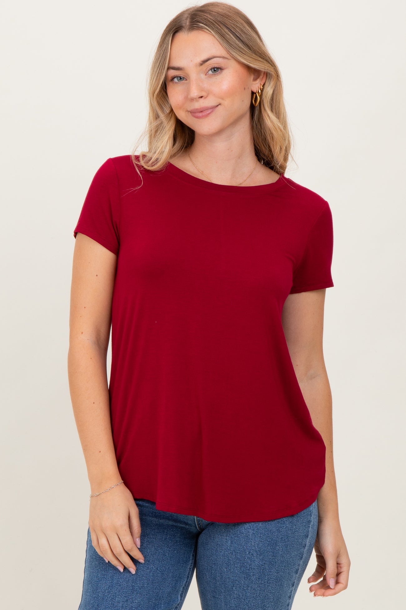 woman wearing a red short sleeve top paired with blue jeans