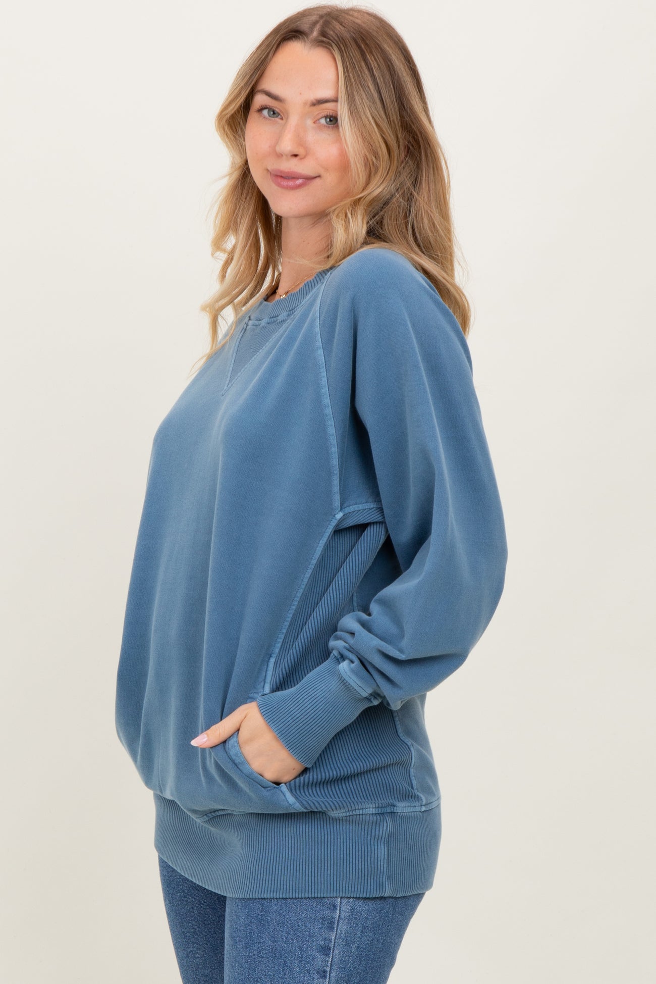 woman wearing a blue oversized sweatshirt with a relaxed fit and side pockets