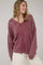woman wearing a loose-fit maroon oversized sweater with a V-neck and contrasting ribbed hem