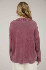 woman wearing a back view of a loose-fitting mauve sweater with a ribbed collar and cuffs