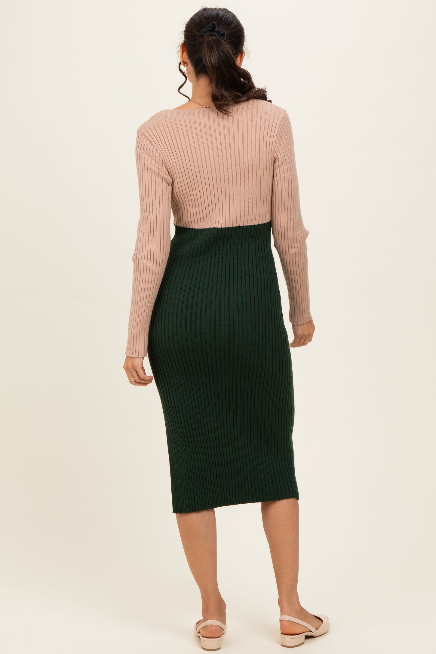woman wearing a pink and green ribbed midi dress with a fitted silhouette and long sleeves, viewed from the back