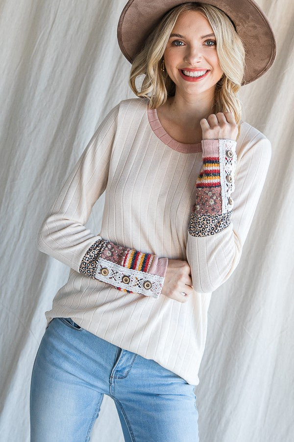 woman wearing a cream ribbed long sleeve top with colorful patterned sleeves and a pink neckline