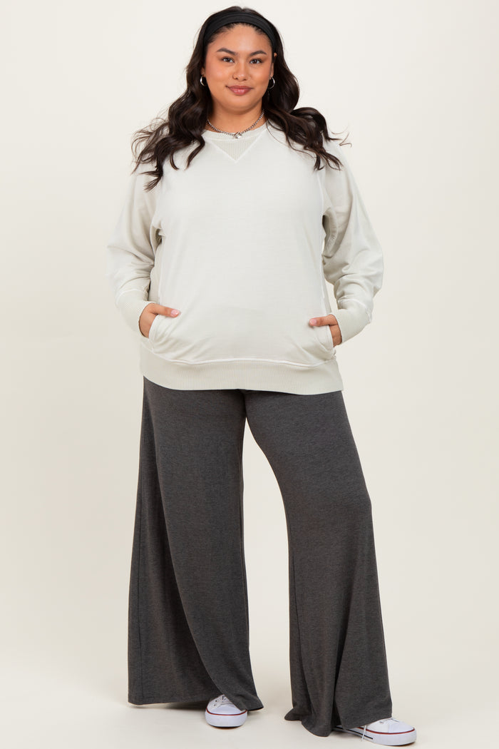 woman wearing a light gray oversized v-neck sweatshirt and dark gray wide-leg pants with pockets