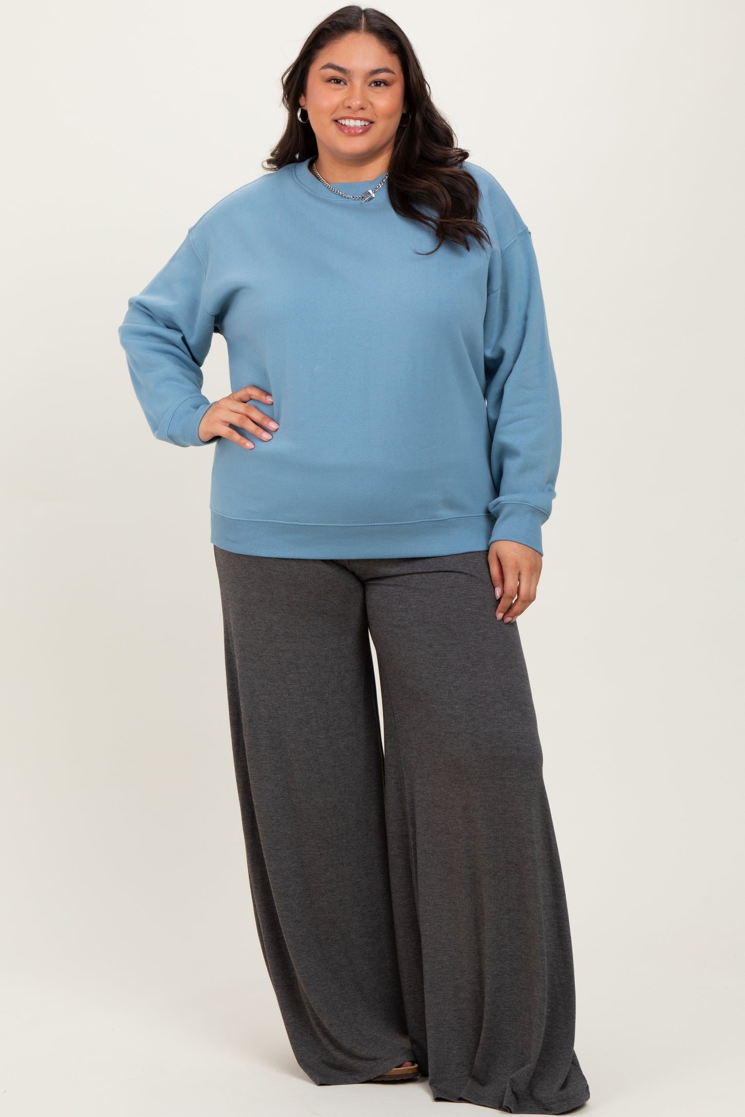 woman wearing a light blue oversized sweatshirt and charcoal gray wide-leg pants