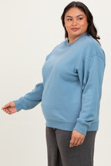 woman wearing a light blue oversized sweatshirt with long sleeves and a relaxed fit paired with dark gray pants