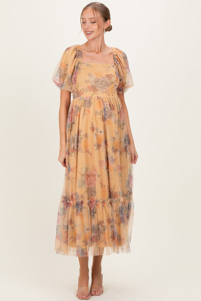woman wearing a yellow floral maternity dress with puff sleeves and a tiered skirt, showcasing her baby bump