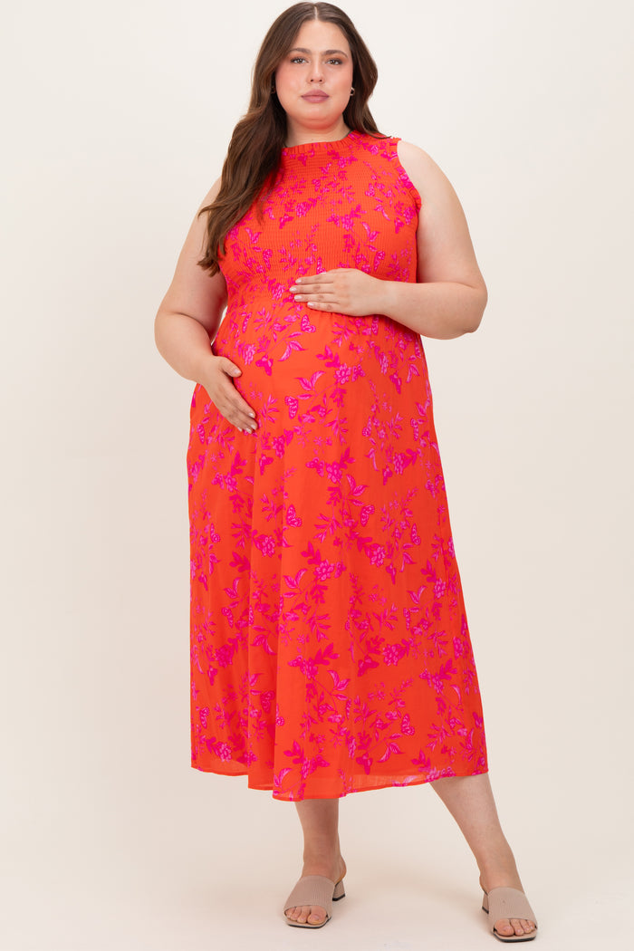 woman wearing a bright coral floral maternity dress with a high neckline and a baby bump visible