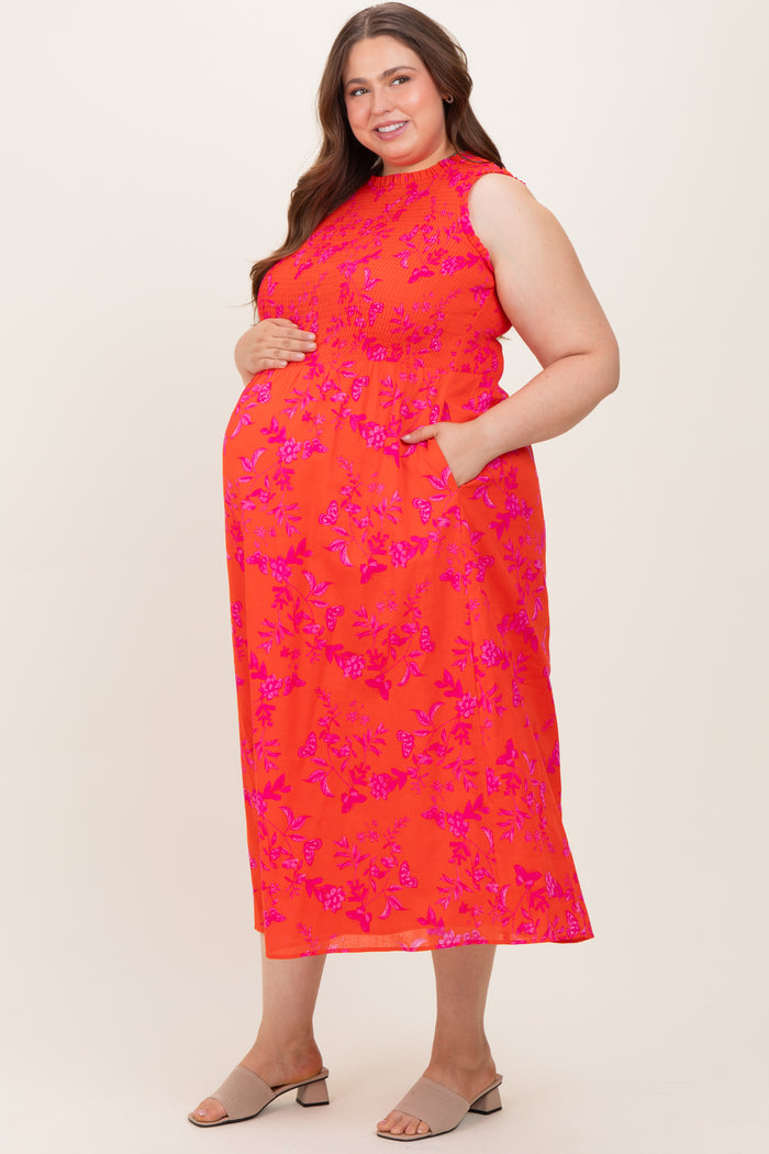 woman wearing a bright orange floral maternity maxi dress with pockets and a baby bump visible