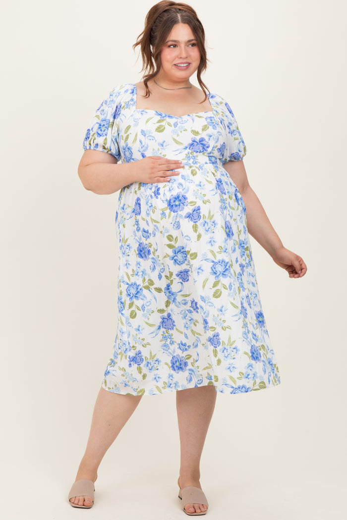 woman wearing a light blue and white floral maternity dress, holding her baby bump