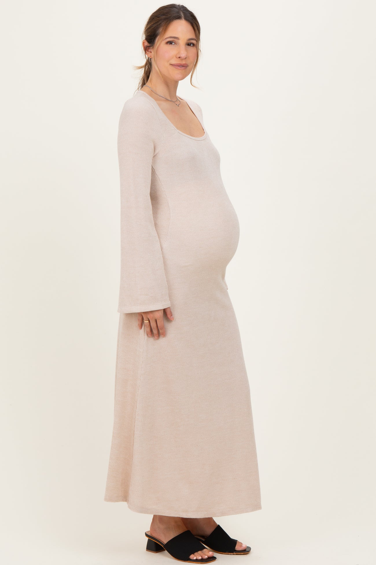 woman wearing a light pink ribbed maternity maxi dress with long sleeves and a visible baby bump