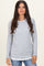 woman wearing a gray long sleeve top with scalloped hem layered over a white shirt and styled with casual jeans
