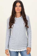 woman wearing a gray long sleeve top with scalloped hem layered over a white shirt and styled with casual jeans