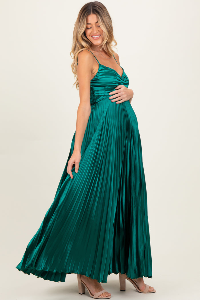 woman wearing a dark green pleated maternity dress with spaghetti straps and a visible baby bump
