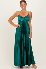 woman wearing a long emerald green pleated dress with spaghetti straps and a fitted bodice