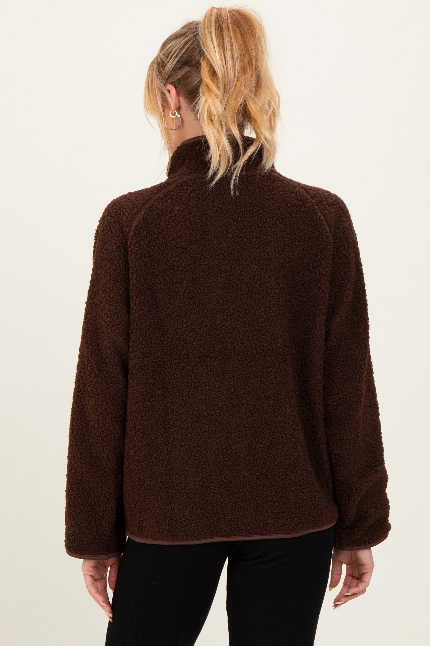 woman wearing a dark brown maternity pullover jacket with a cozy fleece texture and a high collar, seen from the back