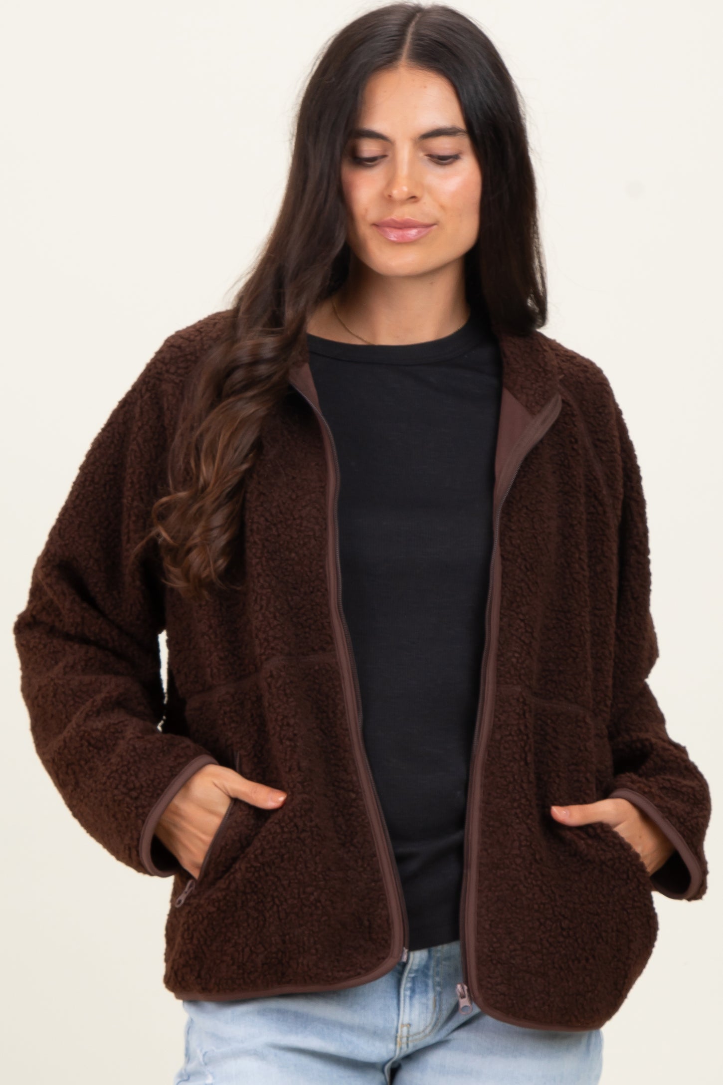 woman wearing a brown fleece zip-up jacket with pockets and a black top underneath