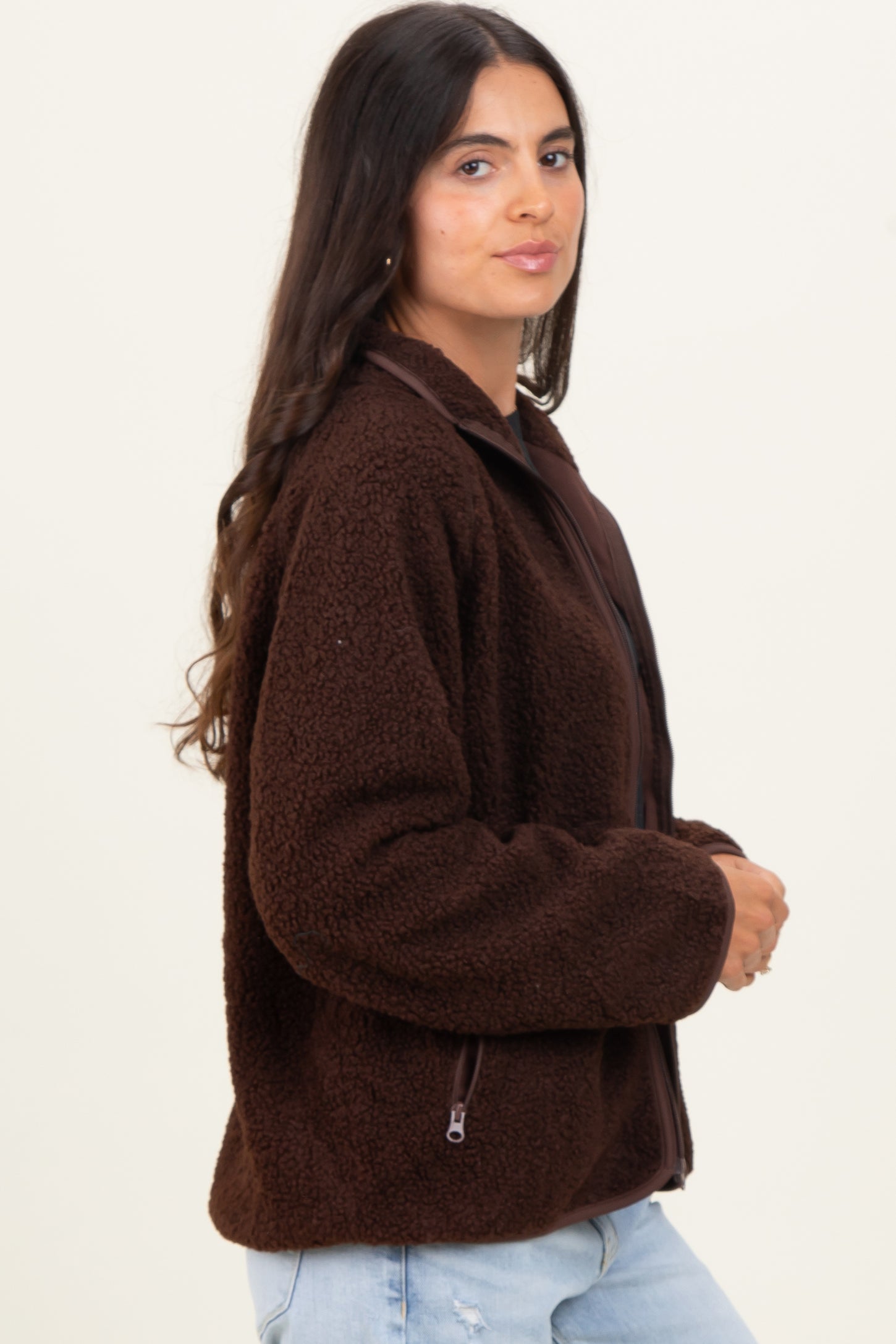woman wearing a brown fluffy zip-up jacket with a high collar and side pockets