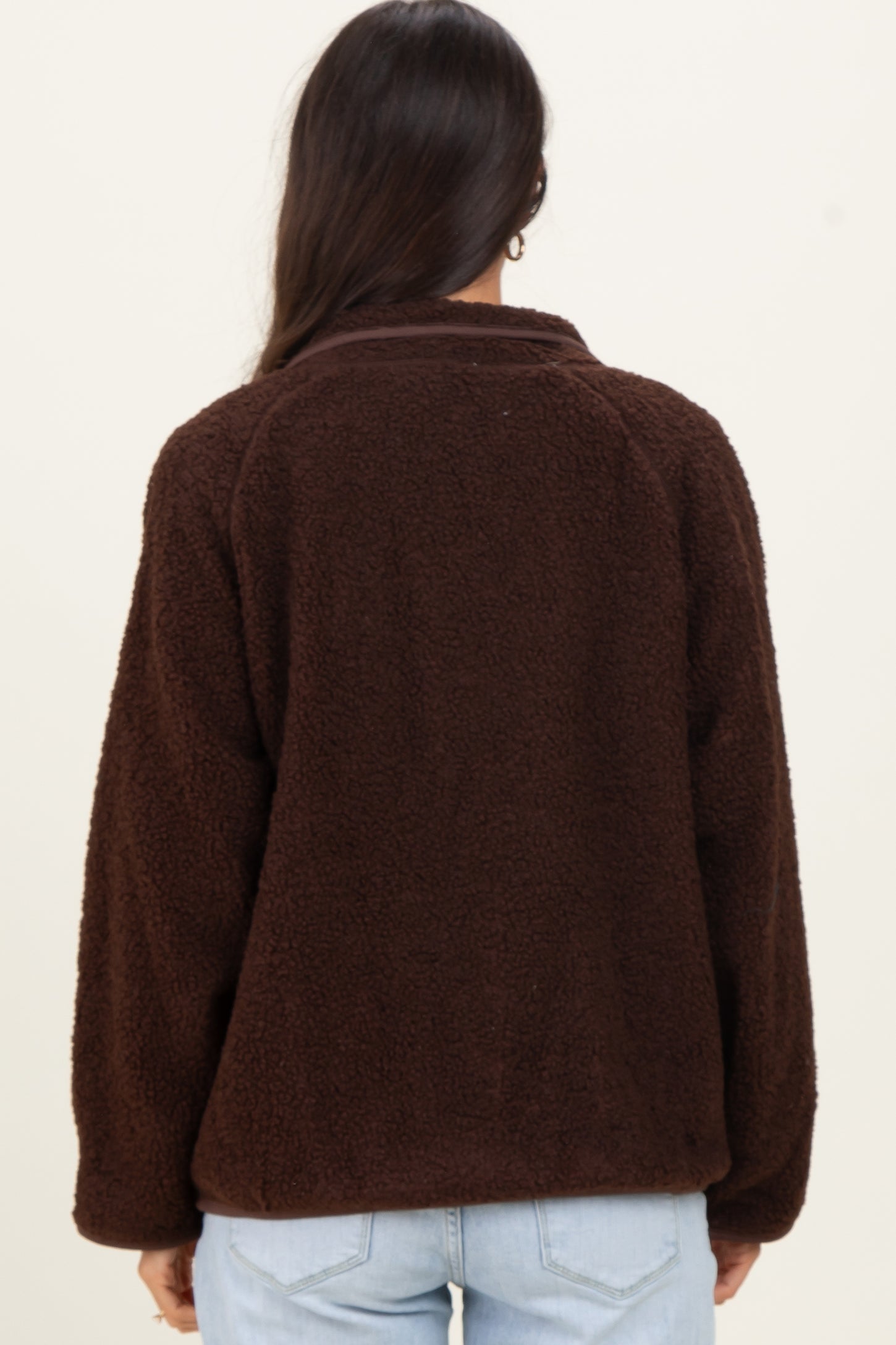 woman wearing a brown fleece jacket with a relaxed fit and collared neckline, view from the back