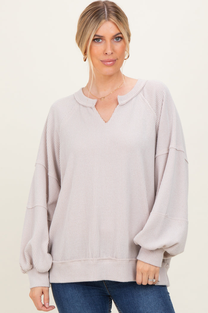 woman wearing a light beige oversized sweater with a v-neck and balloon sleeves, styled with blue jeans