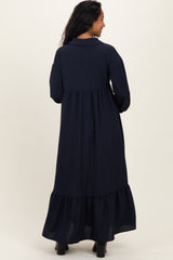 woman wearing a navy blue maternity maxi dress with a tiered bottom and long sleeves, viewed from behind