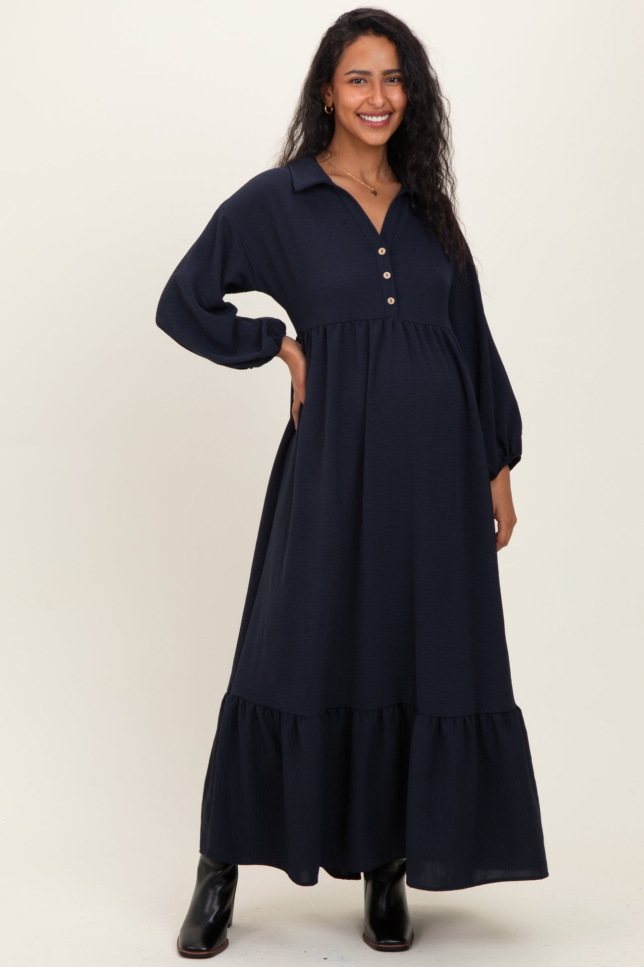 woman wearing a navy blue maternity maxi dress with a collared neckline and button details, showing her baby bump
