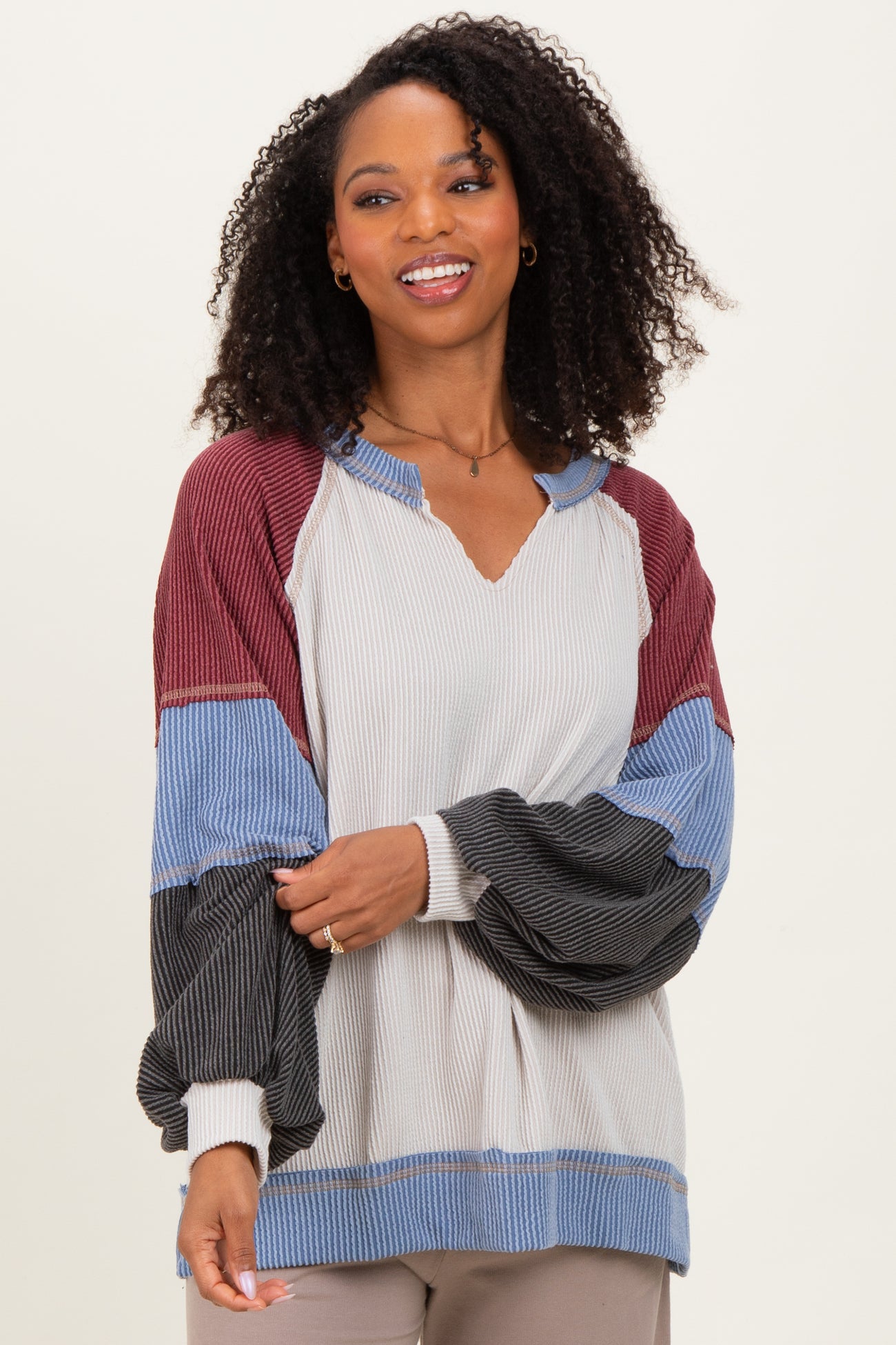 woman wearing a color block long sleeve sweater with a v-neck and puffed sleeves in gray, maroon, and blue