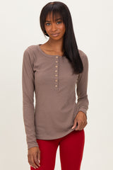 woman wearing a taupe long sleeve henley top with button details and paired with red pants